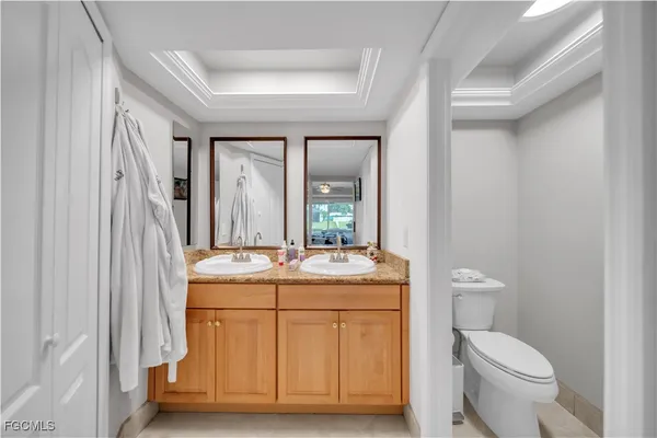 a bathroom with a granite countertop toilet a sink and a mirror