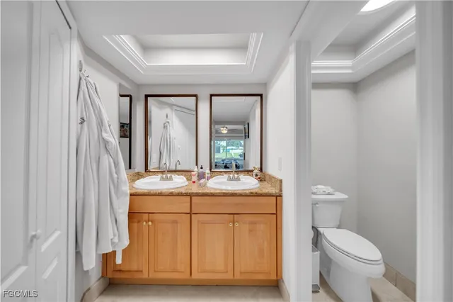 a bathroom with a granite countertop toilet a sink and a mirror