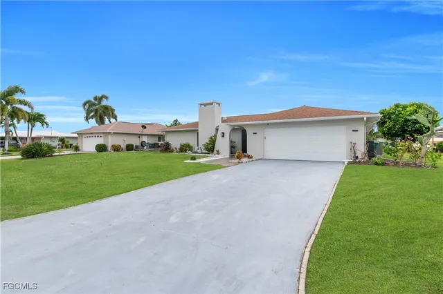 a white house with a big yard plants and big trees