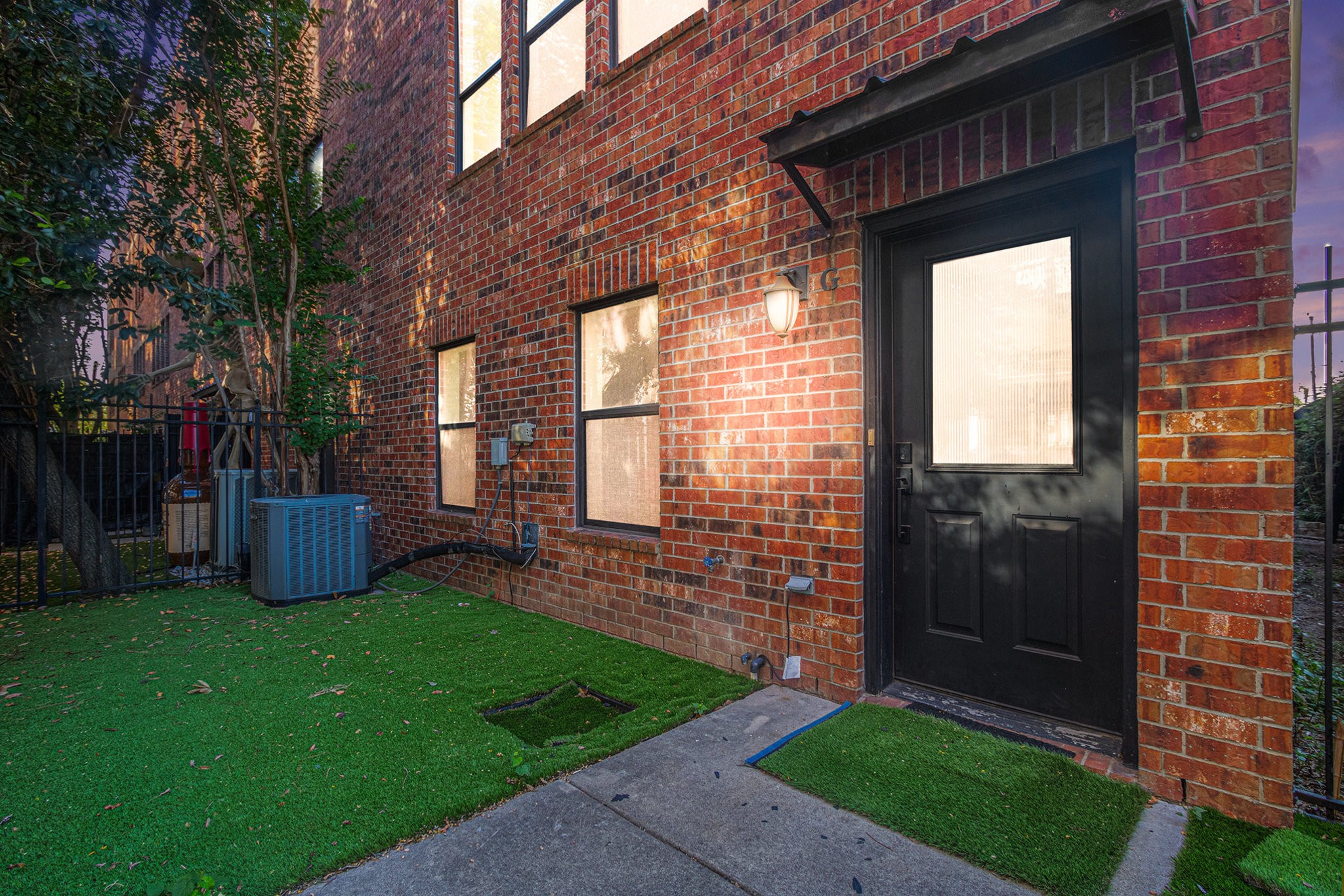 a view of a brick house with a yard and a large tree