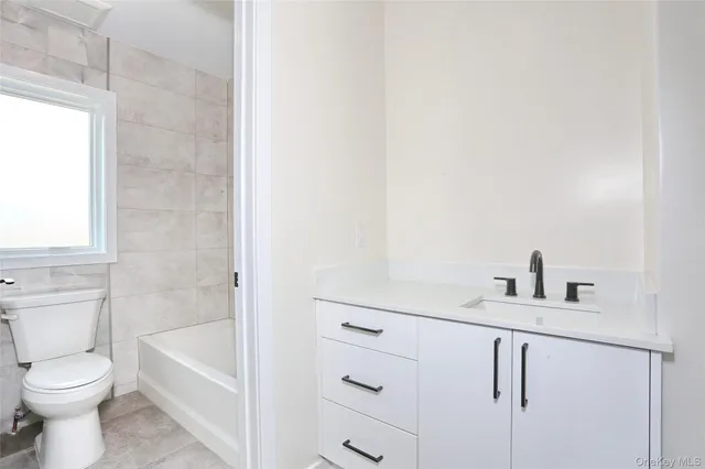 a bathroom with a bathtub sink vanity mirror and toilet