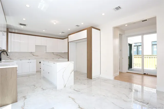 a large white kitchen with a sink large mirror and cabinets