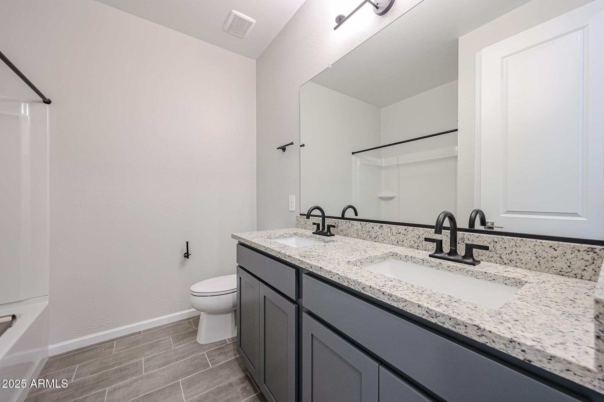 17867 West Fulton Street Goodyear, AZ 85338 - Photo 31 of 40 a bathroom with a granite countertop sink a toilet and a mirror
