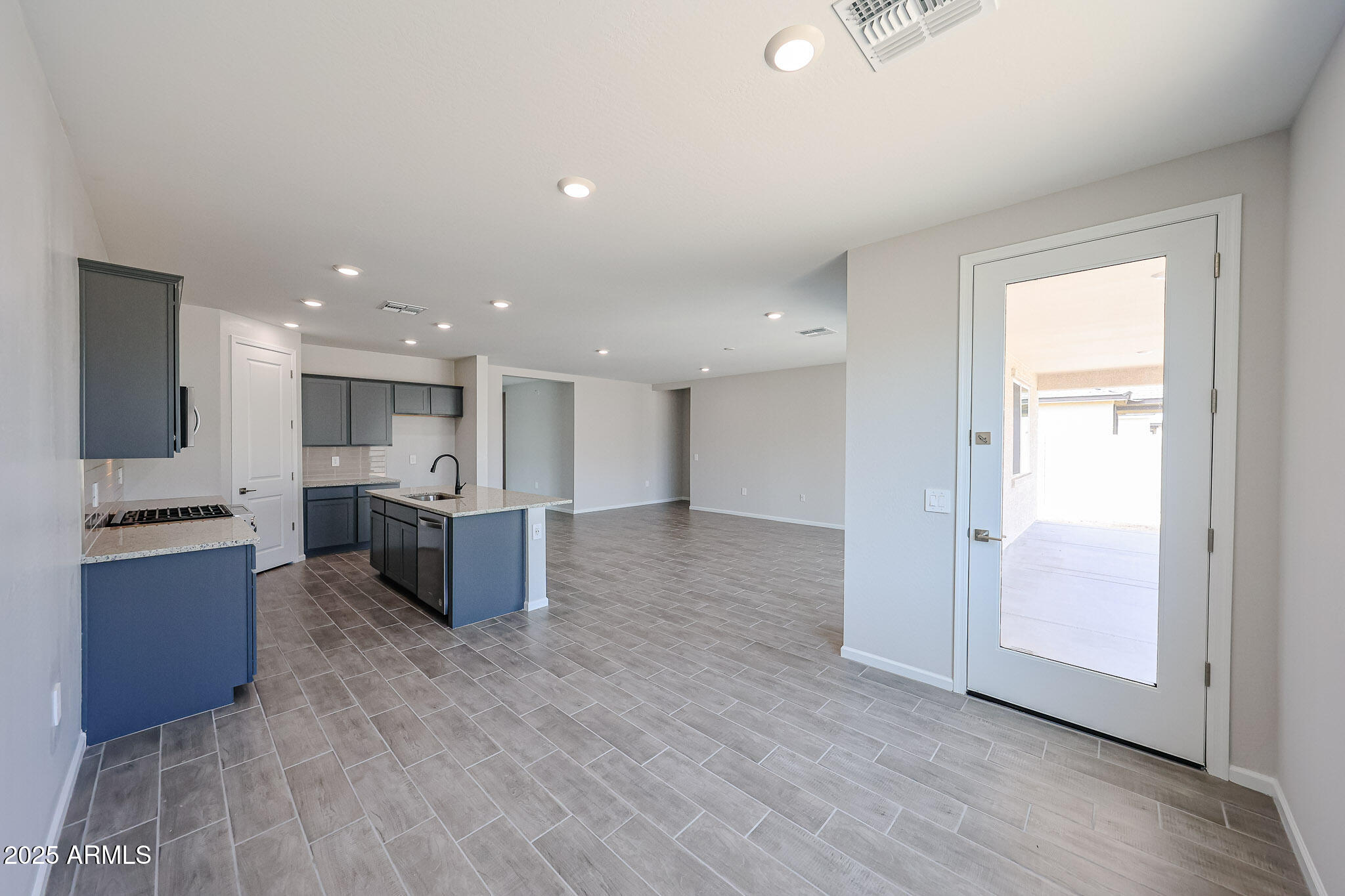 17867 West Fulton Street Goodyear, AZ 85338 - Photo 7 of 40 a open kitchen with stainless steel appliances kitchen island wooden floors and living room view