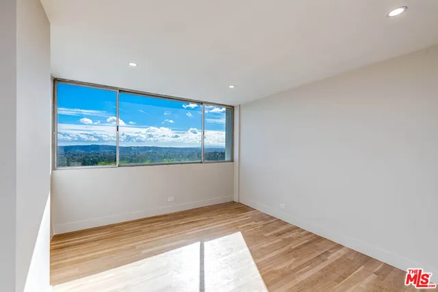 a view of a big room with wooden floor and windows