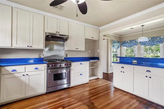 a kitchen with stainless steel appliances white cabinets and wooden floors