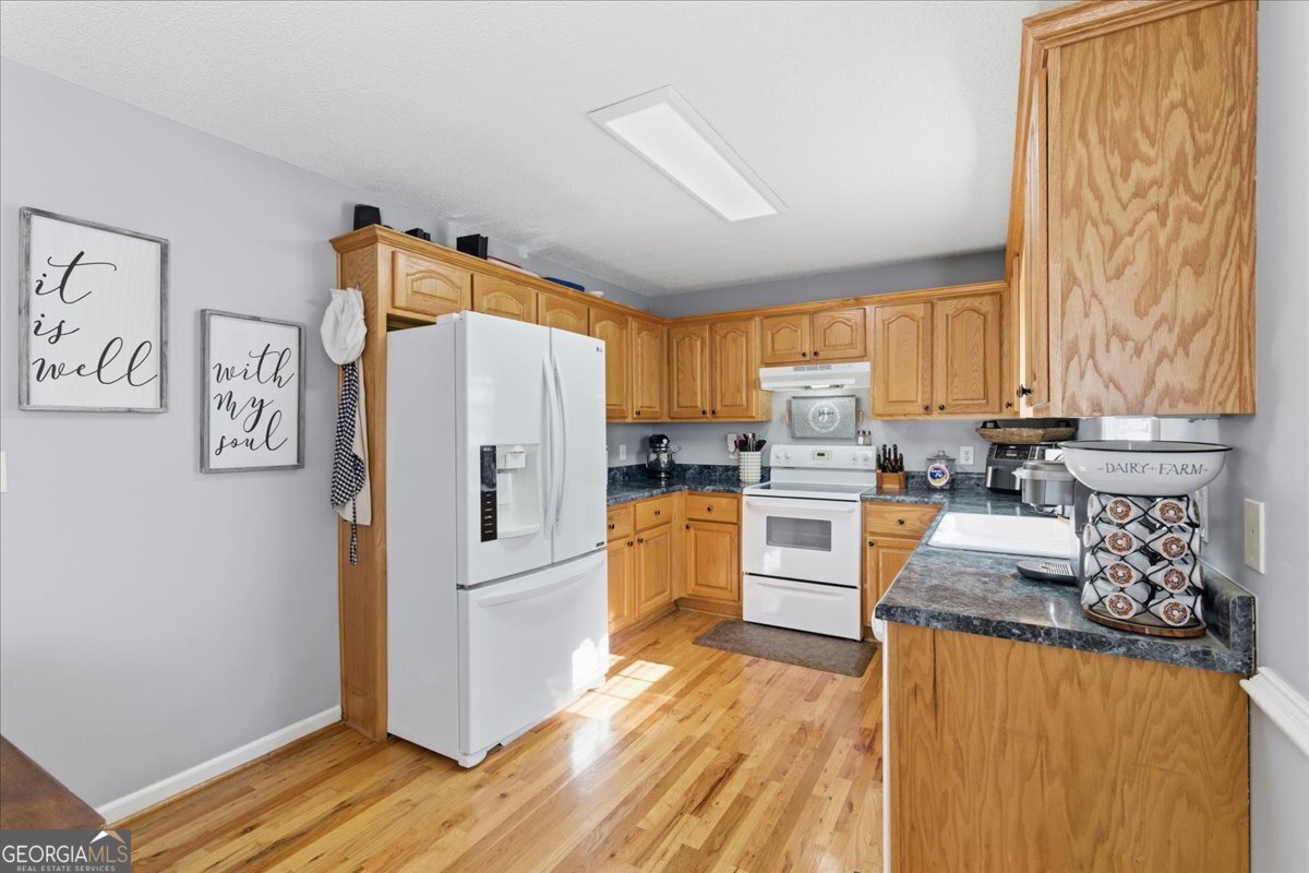 1111 Old Collard Valley Road Aragon, GA 30104 - Photo 12 of 38 a kitchen with granite countertop a refrigerator oven a sink dishwasher and a stove with wooden floor