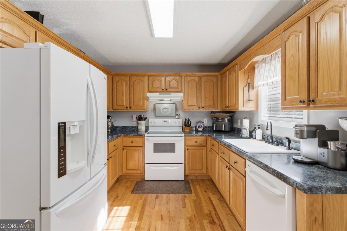 1111 Old Collard Valley Road Aragon, GA 30104 - Photo 13 of 38 a kitchen with stainless steel appliances granite countertop a refrigerator a sink dishwasher a stove and white countertops with wooden floor