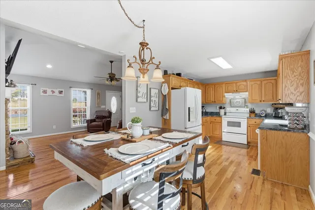 a view of a dining room and livingroom with furniture wooden floor a rug a flat screen tv a painting and a chandelier