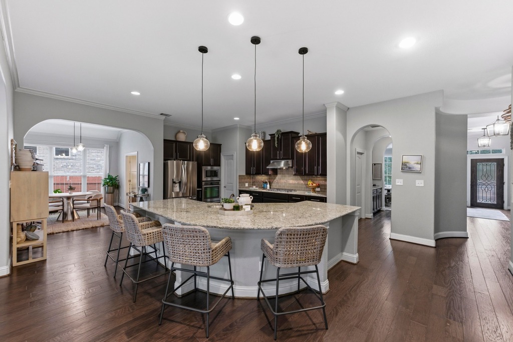 5425 Cherokee Draw Road Austin, TX 78738 - Photo 7 of 40 A sweeping granite kitchen island with pendant lighting anchors this inviting open-concept living space.