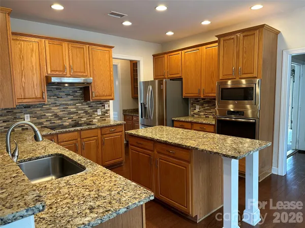 a kitchen with stainless steel appliances kitchen island granite countertop a sink stove and refrigerator