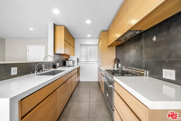 a large kitchen with stainless steel appliances granite countertop a sink a stove and a refrigerator