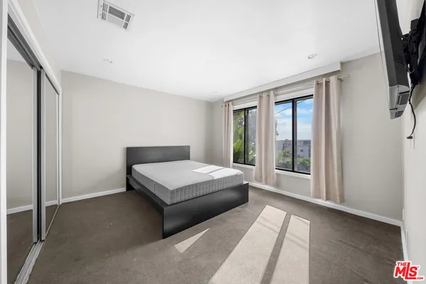 a bedroom with a bed lamp and a large window