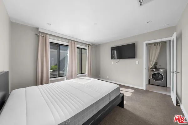 a bedroom with a bed and a flat tv screen on the dresser