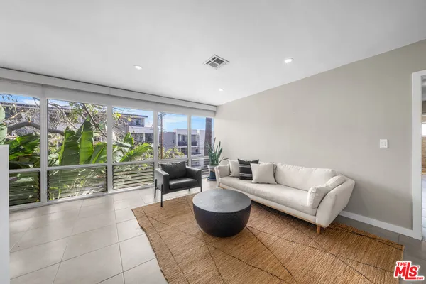 a living room with patio furniture and a potted plant