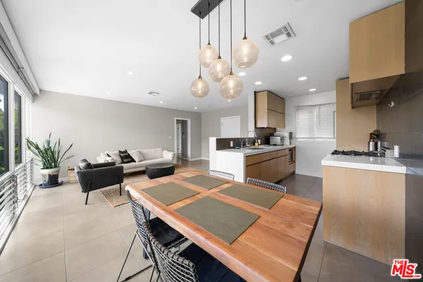 a kitchen with stainless steel appliances kitchen island granite countertop a sink a stove a dining table and chairs with wooden floor