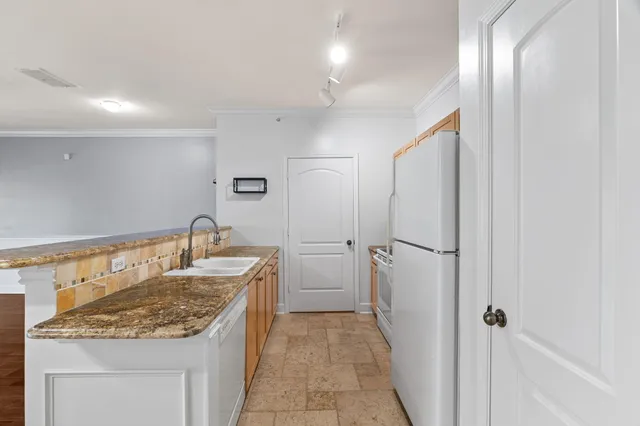 a kitchen with granite countertop a refrigerator and a sink