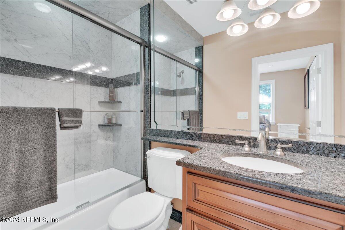 87359 Raddin Road Yulee, FL 32097 - Photo 36 of 80 a bathroom with a granite countertop sink a toilet a mirror and shower