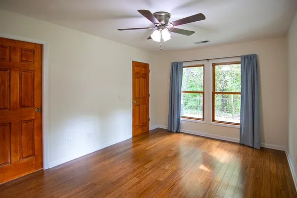 a view of an empty room with wooden floor and a window