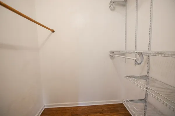 an empty room with wooden floor chandelier fan and windows