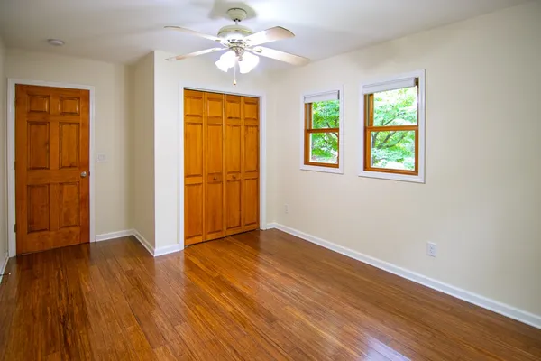 a view of an empty room with wooden floor and a window