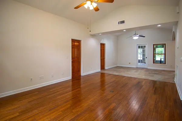 a view of an empty room with window and wooden floor