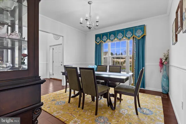 a dining room with furniture a rug a potted plant and a chandelier