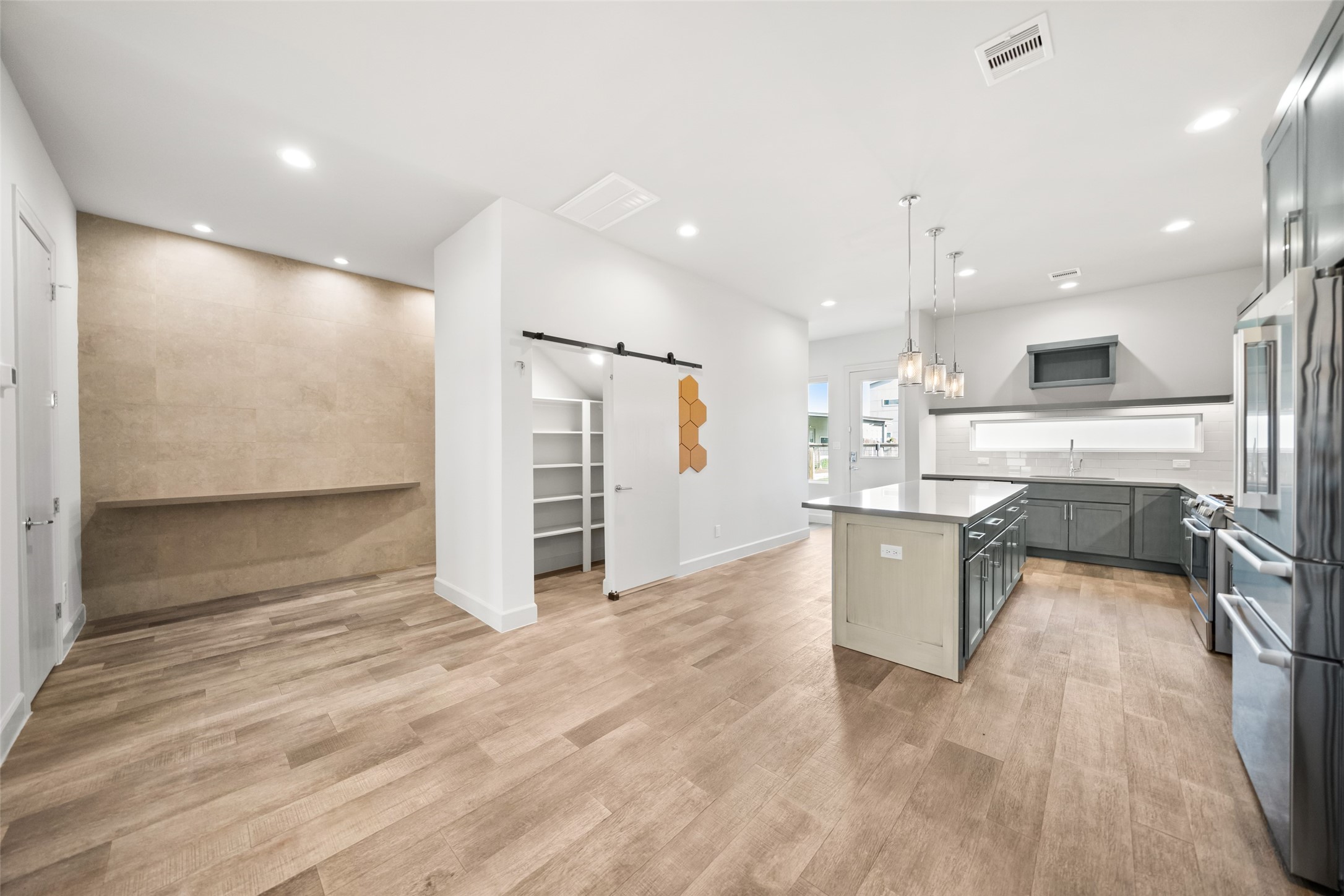 6809 Troya Lane Houston, TX 77092 - Photo 11 of 49 A custom tile accent wall creates a stylish transition leading toward the primary suite. The open layout includes a walk-in pantry with a sliding barn door and seamless flow into the kitchen, perfect for both daily living and entertaining.
