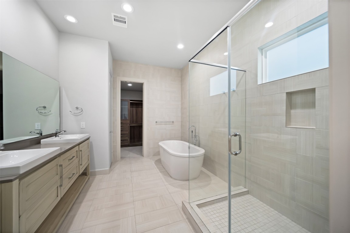6809 Troya Lane Houston, TX 77092 - Photo 23 of 49 The spa-like primary bath features a freestanding soaking tub, oversized walk-in shower, double vanity, and elegant tilework throughout—leading seamlessly into a custom walk-in closet.