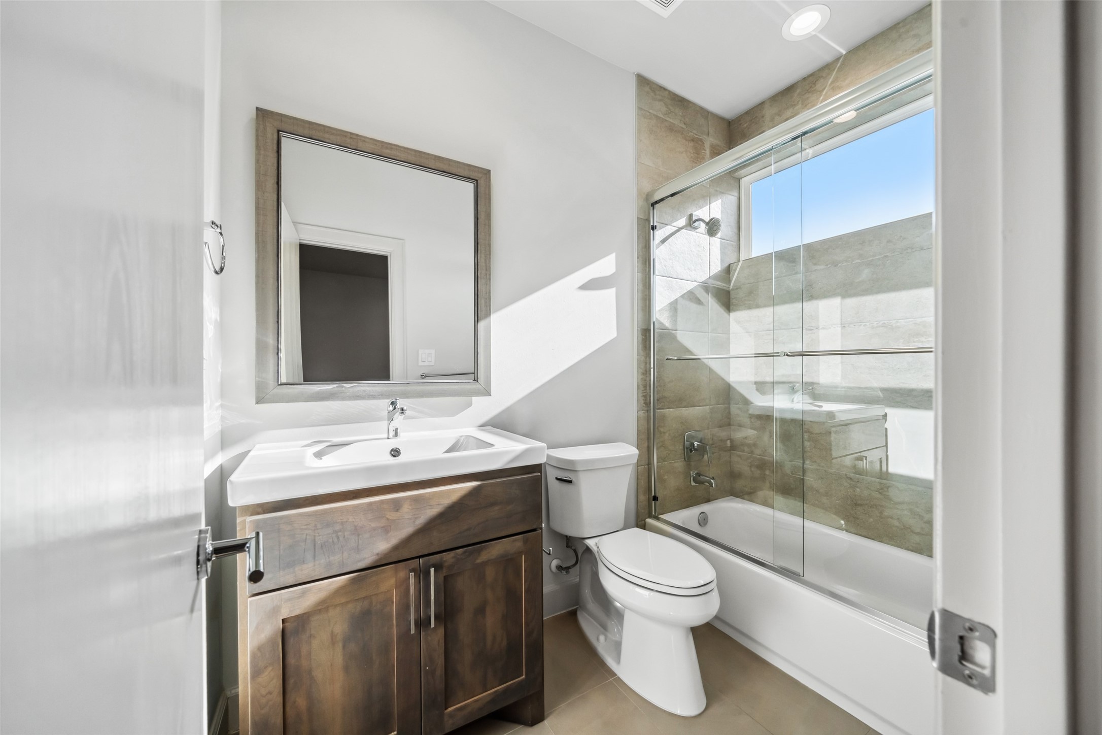 6809 Troya Lane Houston, TX 77092 - Photo 33 of 49 Stylish en-suite bath featuring a full-height tiled shower wall, sleek glass enclosure, and rich dark wood vanity.