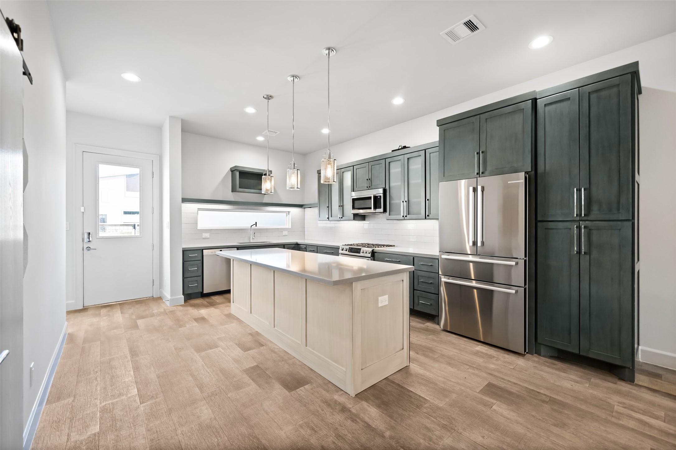 6809 Troya Lane Houston, TX 77092 - Photo 10 of 49 Beautifully designed kitchen with upgraded cabinetry, quartz countertops, a spacious island, and a brand-new stainless steel refrigerator. Thoughtful finishes like pendant lighting and sleek hardware add a polished touch.