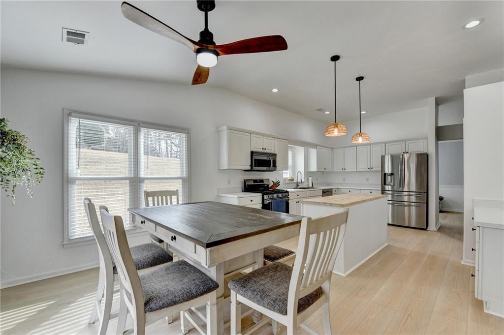 6435 Dressage Crossing Cumming, GA 30040 - Photo 12 of 35 a kitchen with a dining table chairs sink and refrigerator