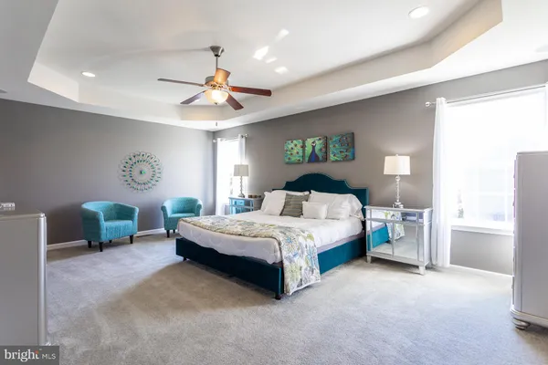 a spacious bedroom with a bed a chandelier and a dresser