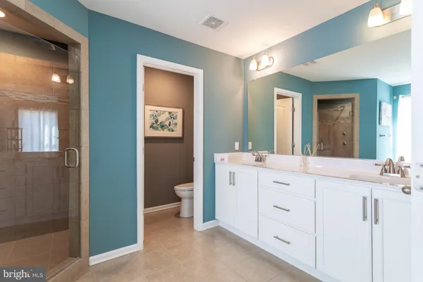 a spacious bathroom with double vanity a mirror and a shower