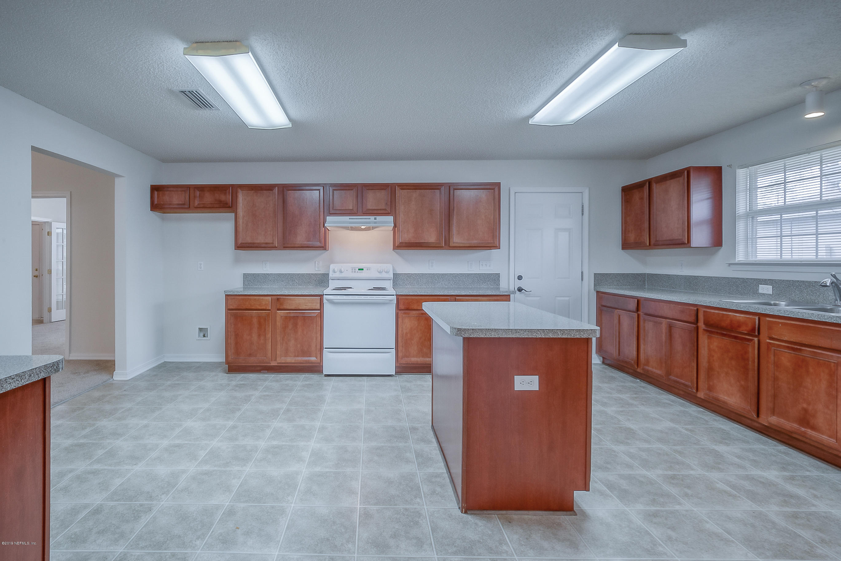 2633 Springwillow Drive Jacksonville, FL 32221 - Photo 9 of 33 a large room with kitchen island granite countertop wooden cabinets a sink a window and stainless steel appliances