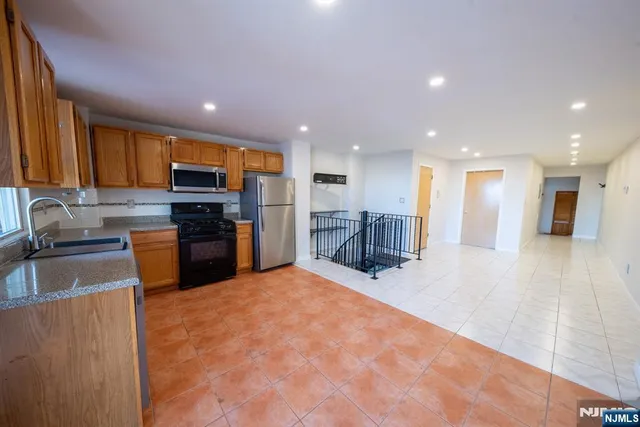 a kitchen with stainless steel appliances granite countertop a sink refrigerator and cabinets