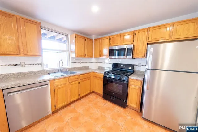 a kitchen with granite countertop stainless steel appliances a refrigerator sink and microwave