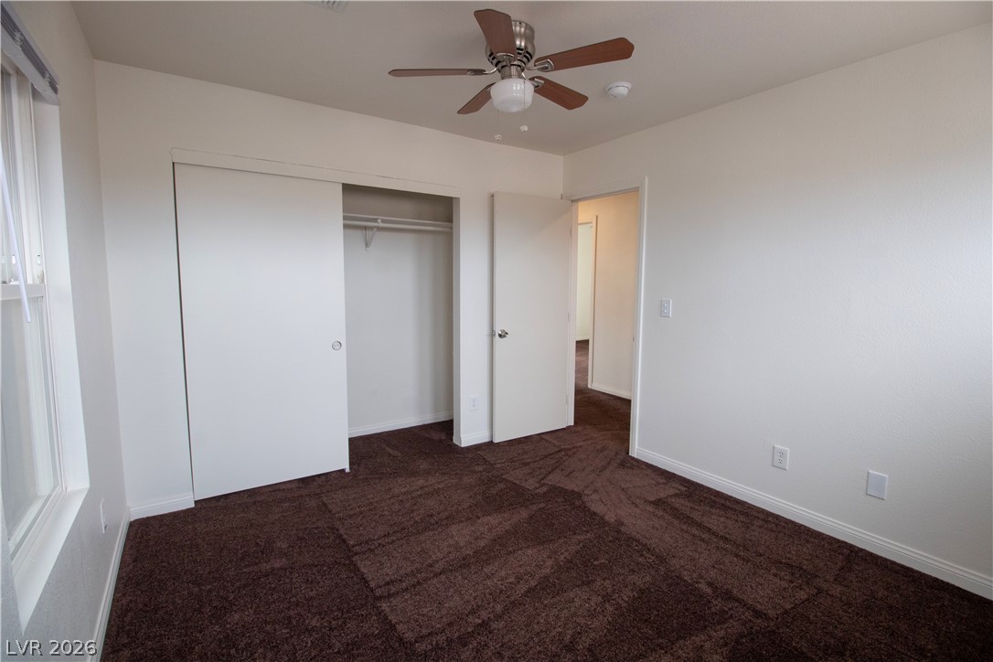 119 West Victory Road Henderson, NV 89015 - Photo 18 of 26 A well-lit bedroom features plush brown carpeting and an integrated ceiling fan.