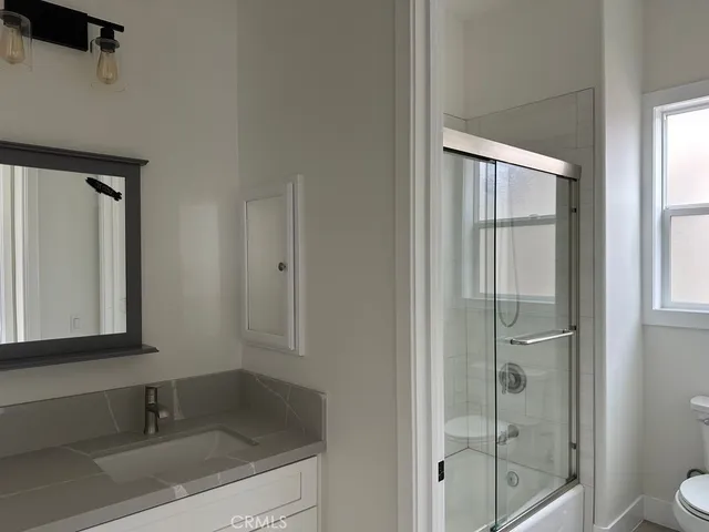 a bathroom with a granite countertop sink toilet and shower