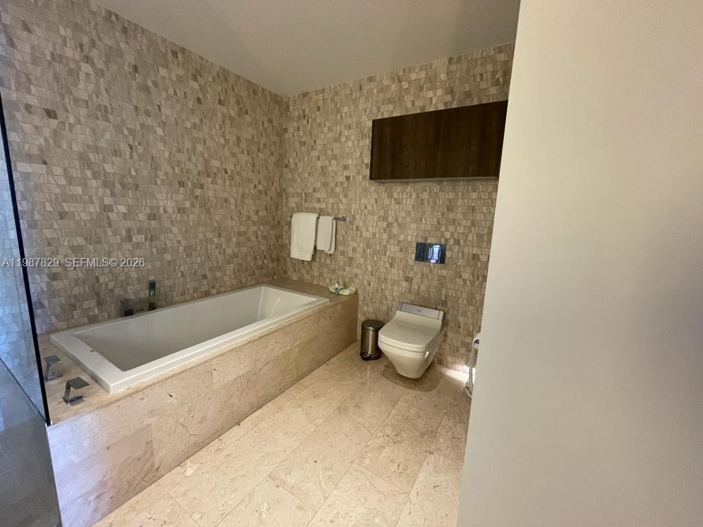 88 Southwest 7th Street, Unit 3609 Miami, FL 33130 - Photo 7 of 25 a spacious bathroom with a bathtub and a flat screen tv
