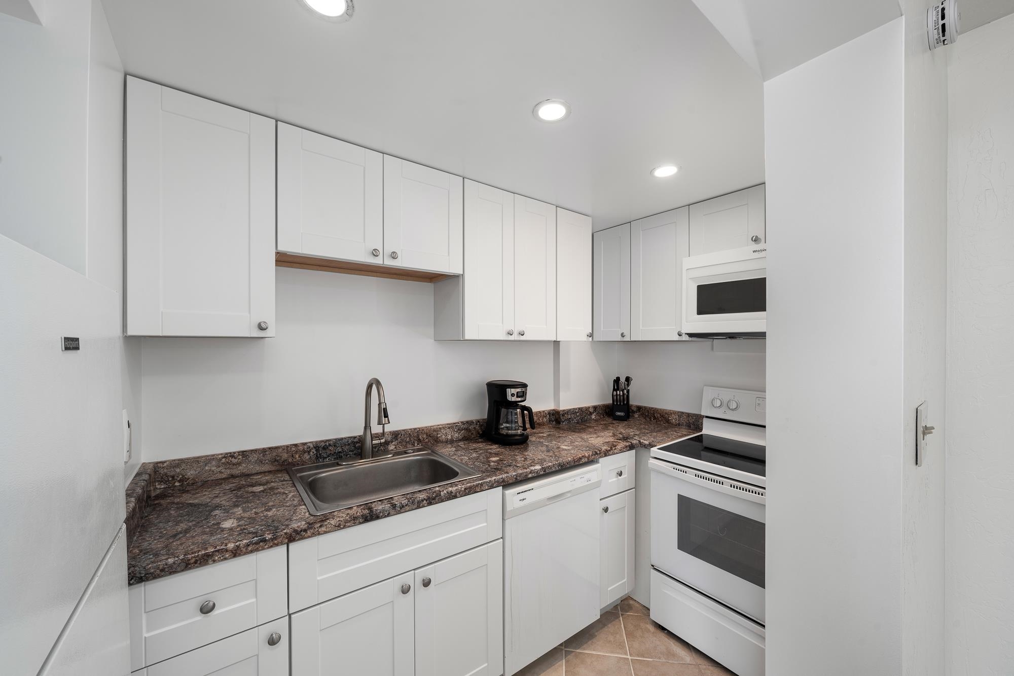 3723 Lower Honoapiilani Road, Unit 104 Lahaina, HI 96761 - Photo 9 of 45 a kitchen with granite countertop white cabinets and white appliances