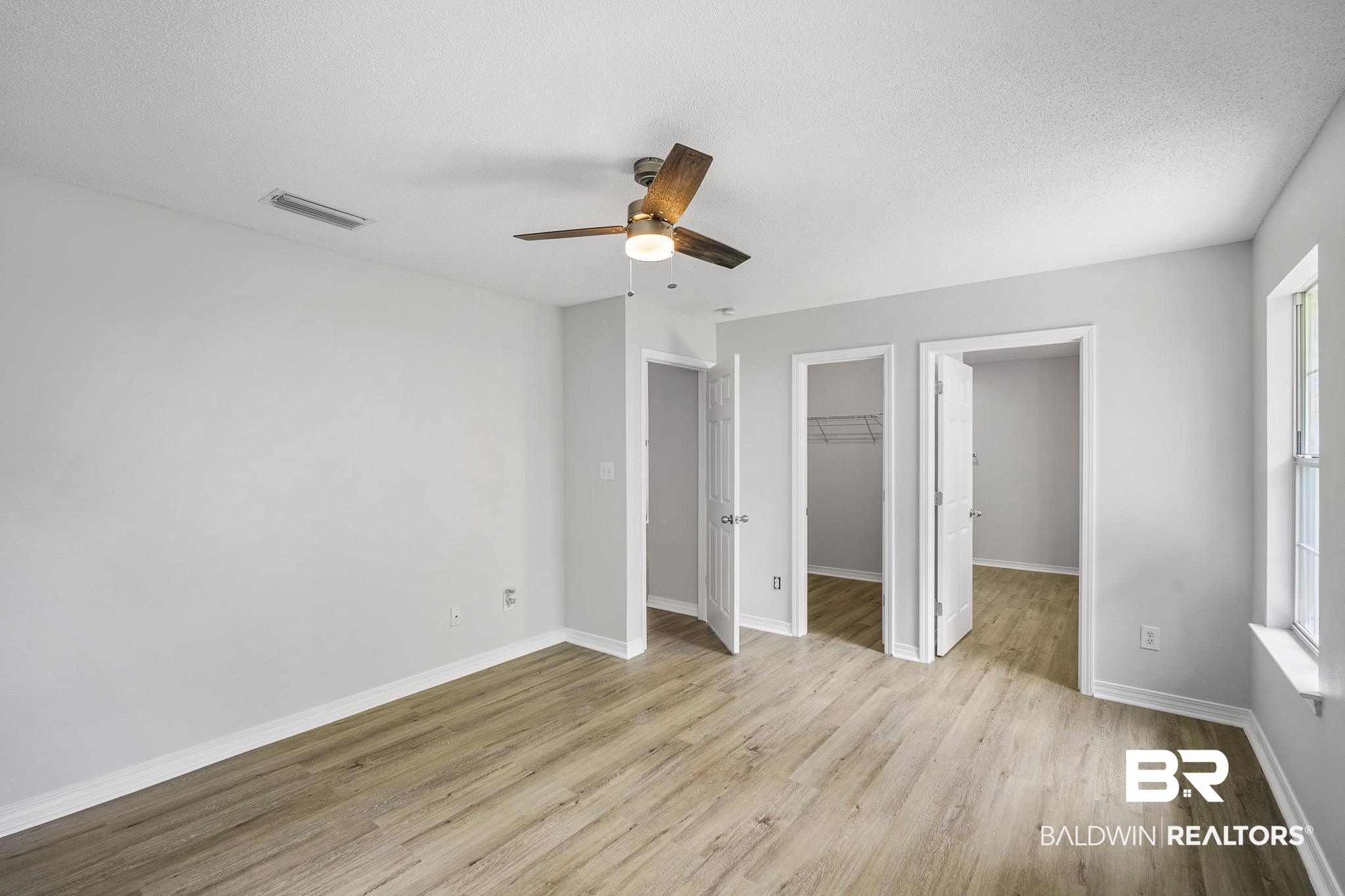 9814 Woolrich Avenue Fairhope, AL 36532 - Photo 19 of 29 Unfurnished bedroom featuring light hardwood / wood-style floors, a spacious closet, ceiling fan, and a closet