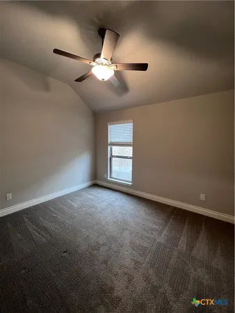 an empty room with a window and ceiling fan