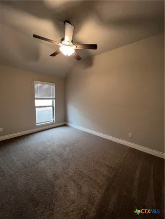 an empty room with a chandelier fan and windows