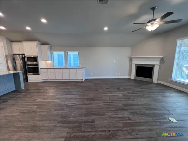 an empty room with wooden floor fireplace and windows