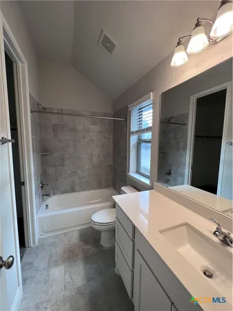 a bathroom with a bathtub shower sink vanity mirror and toilet