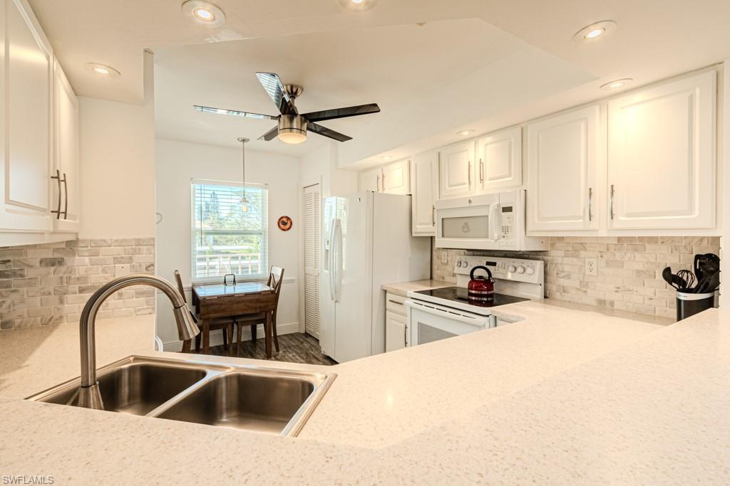 a kitchen with stainless steel appliances a sink a stove a refrigerator cabinets and a window