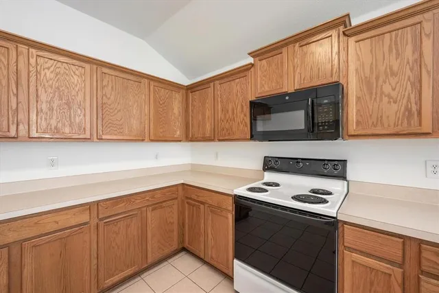 a kitchen with a sink dishwasher stove and microwave with wooden cabinets