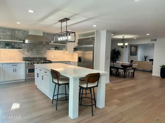 a kitchen with stainless steel appliances a dining table chairs stove and white cabinets
