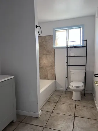 an empty room with a kitchen and chandelier fan